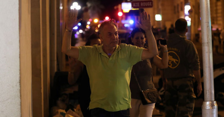 A man walks with his hands up as police officers carry out checks on people in the centre of French Riviera town of Nice, after a van that ploughed into a crowd leaving a fireworks display on July 14, 2016. At least 60 people are feared dead after a van drove into a crowd watching Bastille Day fireworks in the French resort of Nice on July 14, authorities said on July 15. / AFP PHOTO / Valery HACHE