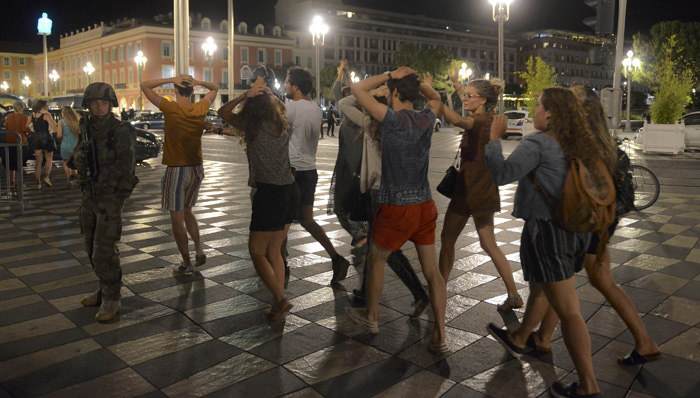 People cross the street with their hands on thier heads as a French soldier secures the area July 15, 2016 after at least 60 people were killed along the Promenade des Anglais in Nice, France, when a truck ran into a crowd celebrating the Bastille Day national holiday July 14.  REUTERS/Jean-Pierre Amet